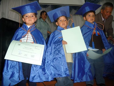 small children in caps and gowns holding diplomas