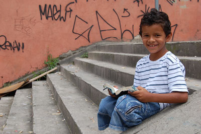 smiling boy sitting on steps reading a book