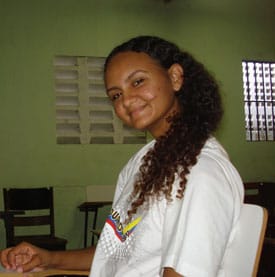 Young lady sitting at a desk inside a classroom.