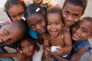Group of young children crowded together smiling up at the camera