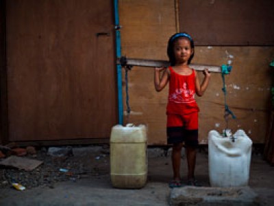 small girl carrying two large water containers