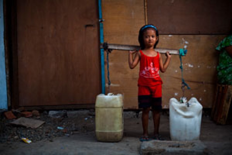 small girl carrying two large water containers