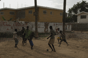 children playing soccer on dirt lot
