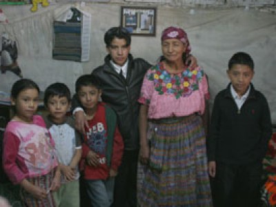 Young man with his 4 younger siblings and grandmother standing in their home