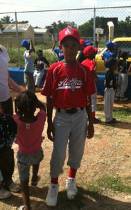 boy in baseball uniform with little girl standing next to him