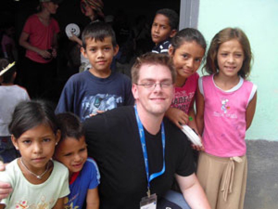 Several young children around a young man.