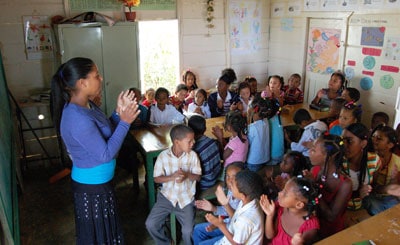 woman standing in front of group of children in a classroom