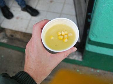 a person's hand holding a warm drink made with corn and cinnamon