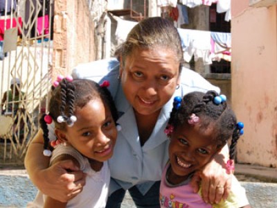 woman stooping down to give girls a hug