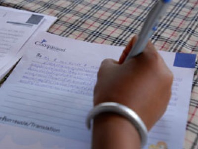 a hand holding a pen writing a Compassion letter