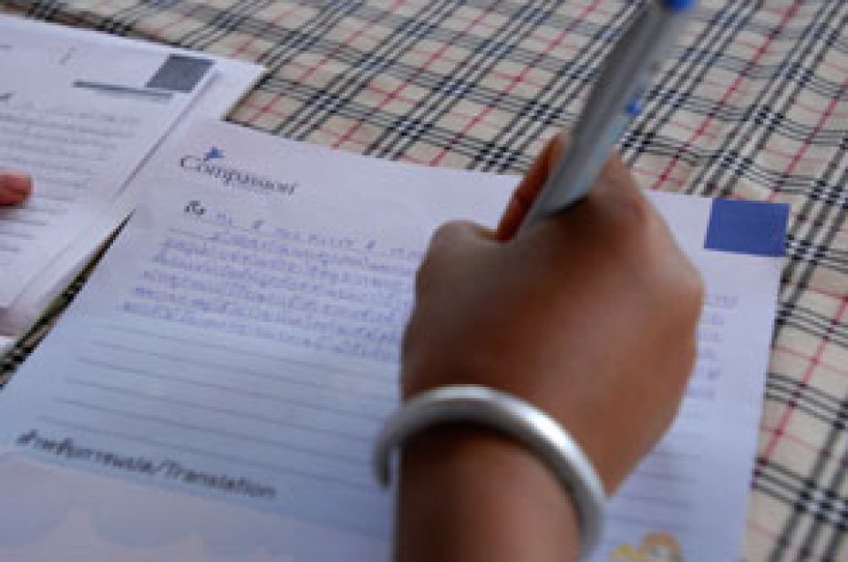 a hand holding a pen writing a Compassion letter