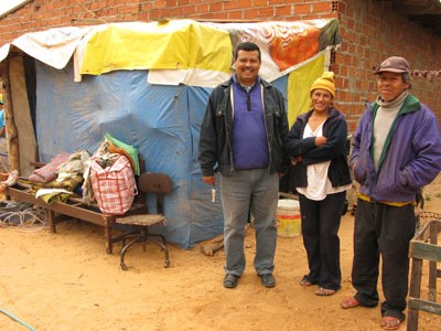 three people standing next to a bench and a structure covered with blue and yellow material