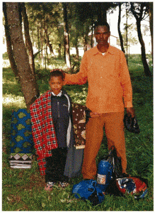 A man and boy stand amongst trees with items at their feet