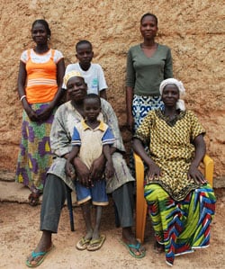 family of six with mom and dad sitting and three children standing and one child in the lap of the father