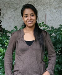 Young lady standing by a wall of plants.