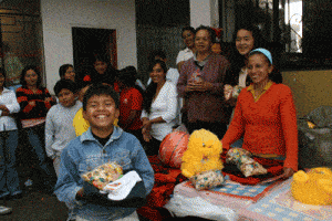 group of children being given gifts with one boy smiling and showing his gift