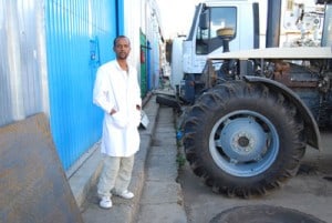 man in white coat standing by heavy equipment vehicle