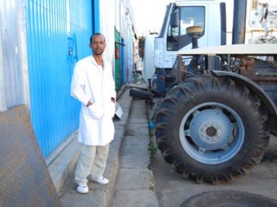 young man standing by tractor and large truck