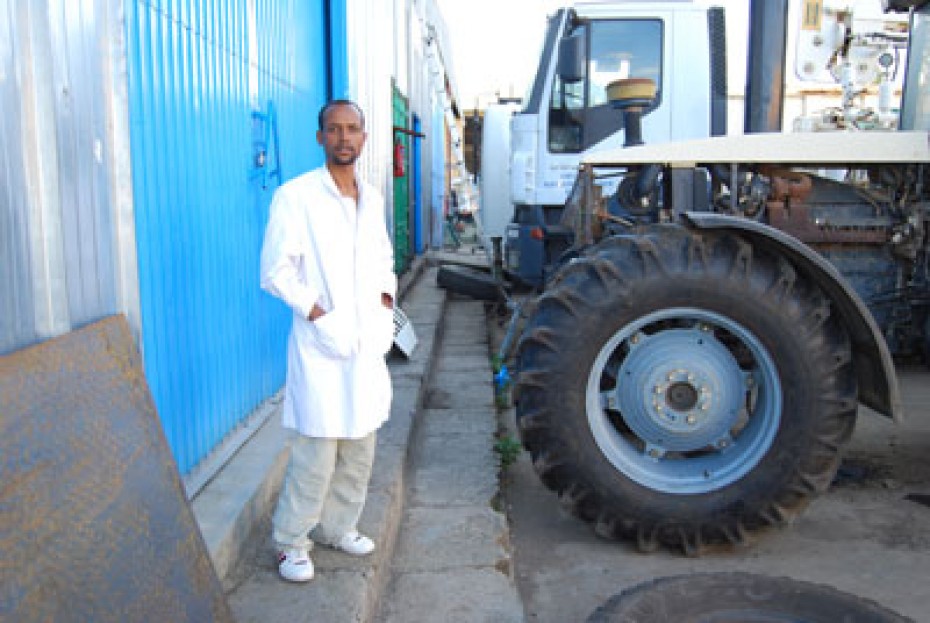 young man standing by tractor and large truck