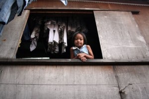 girl looking from an open window with laundry hanging behind her