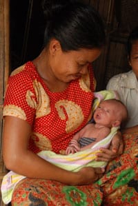 Young mother with a big smile holding her newborn baby