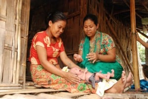 Young mother in red with her newborn baby getting assistance by a health worker