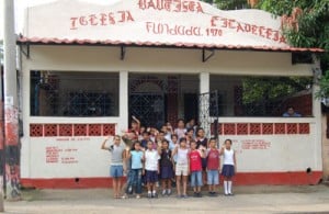 group of childen waving from front of student center