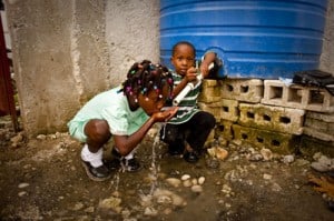 two children drinking water using their hands
