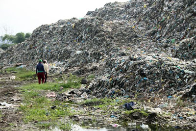 two people standing by a mountain of trash