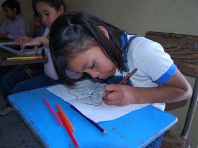 young girl sitting at desk drawing