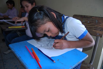 young girl sitting at desk drawing