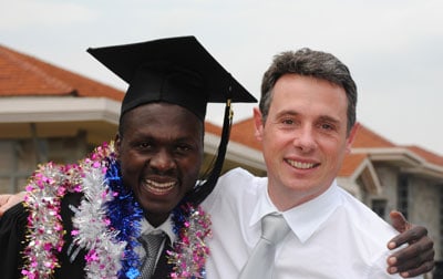 man in tie embracing a young man in graduation gown