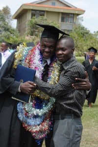 man in graduation gown embracing another young man
