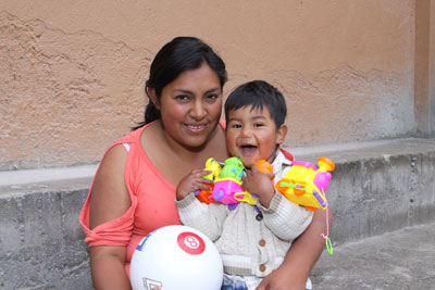 woman holding a soccer ball and a toddler holding toys and laughing