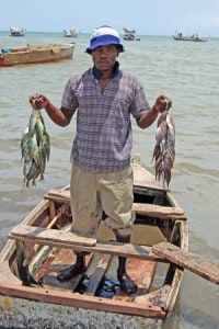 man holding fish and standing up in boat