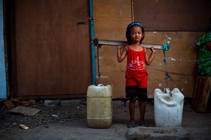 young girl standing next to water containers