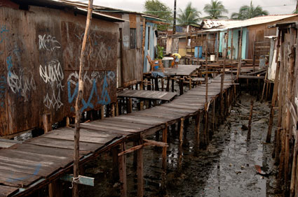 wooden walkway over sewage between houses in slums