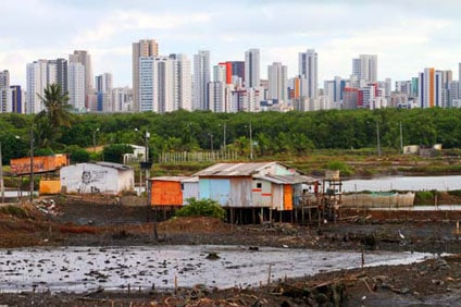 raised homes in the mud with cityscape in the background