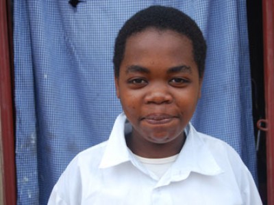 Young boy standing outside of a doorway.