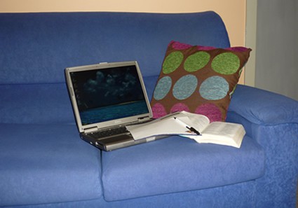 Laptop and book on a blue couch.