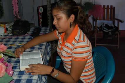young woman sitting at a table reading a Bible