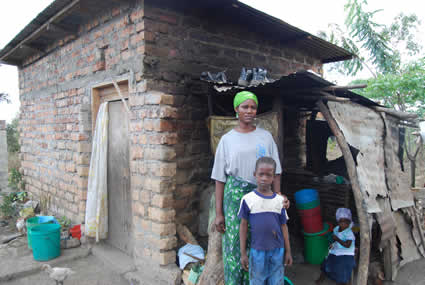 woman, boy and small child standing outside of house