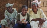 boy sitting with two women in Burkina Faso