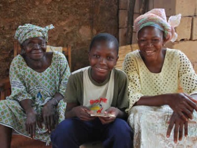 boy sitting with two women in Burkina Faso