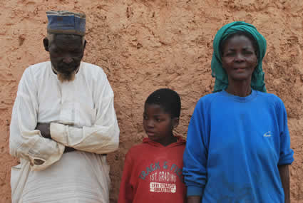 boy wearing red shirt standing with elderly man and woman in blue shirt