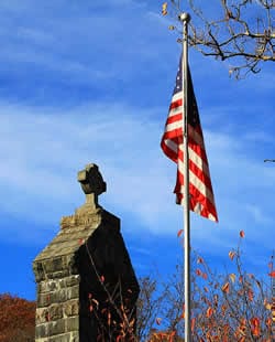 US flag next to a stone memorial