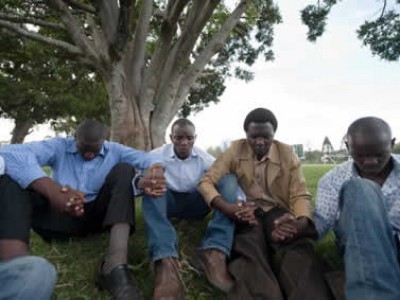 group of men sitting on the ground praying