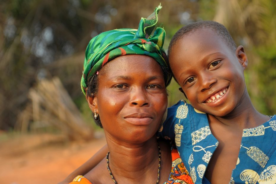 Shunammite woman: A woman wearing a green head scarf holds a smiling boy wearing a green shirt in her arms.