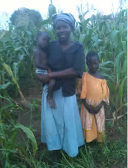 woman holding a baby standing next to girl in cornfield