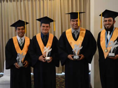 four male graduates posing for camera with awards